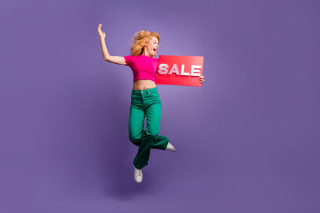 Photo of charming glad adorable woman wear stylish clothes hold banner isolated on purple color...