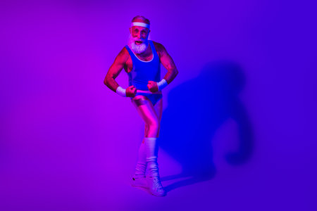 Dynamic retro fitness man in blue poses under purple blue neon lights for stock useの写真素材