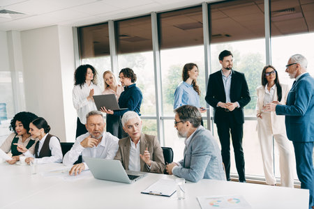 Diverse team of businesspeople collaborating in a modern office environment, discussing strategies...