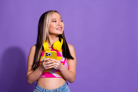 Photo of charming cheerful girl wear trendy clothes use phone look empty space isolated on purple...