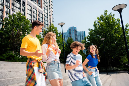 A cheerful group of friends enjoying a sunny day outdoors in the city surrounded by urban architectureの写真素材