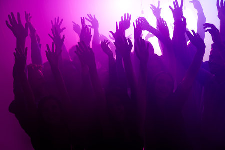 Energetic nightclub crowd dancing under purple lights at a lively party with friends and club vibeの写真素材