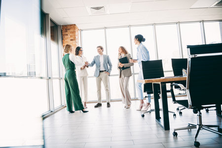 Professional business colleagues engaging in a discussion within a modern office spaceの写真素材
