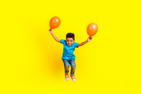 Full size photo of positive small schoolboy wear casual blue t-shirt denim pants holding balloons...