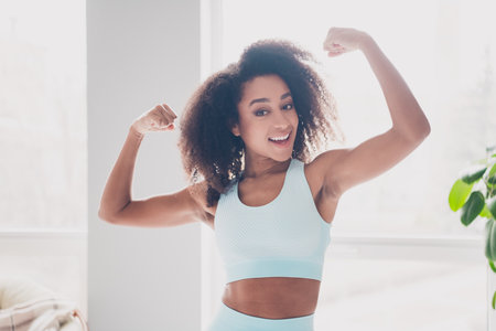Photo of nice fit young woman hands flexing biceps sportswear training home gym indoorsの写真素材