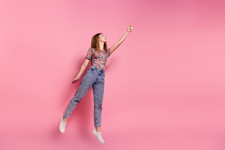 Full length photo of lovely teen lady jump fly dressed stylish print clothes isolated on pink color backgroundの写真素材