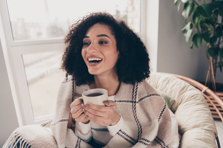 Photo portrait of attractive young woman sit armchair drink tea have fun dressed casual clothes cozy day light home interior living roomの写真素材