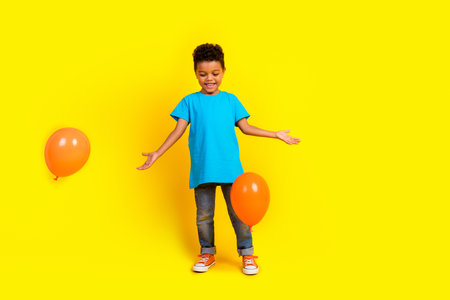 Full body photo of optimistic adorable little child dressed blue t-shirt jeans play with bubbles isolated on vibrant yellow backgroundの写真素材
