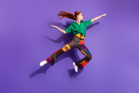 Full size photo of good mood cheerful woman jump raising fist fluttering hair look empty space offer...