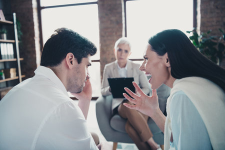 Portrait ofyoung married couple scream fight consultation visit psychotherapist loft interior office indoorsの写真素材