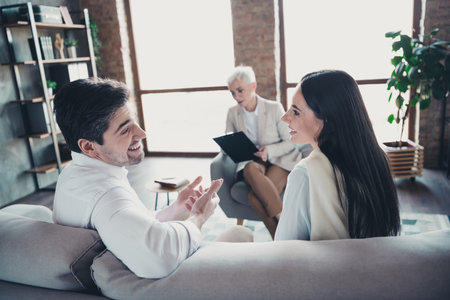 Portrait ofyoung married couple consultation visit psychotherapist sit sofa loft interior office indoorsの写真素材