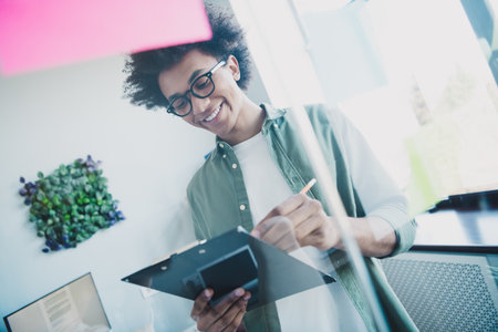 Photo of cool smart employee wear khaki shirt eyeglasses preparing contract signing papers indoors workstation workplaceの写真素材