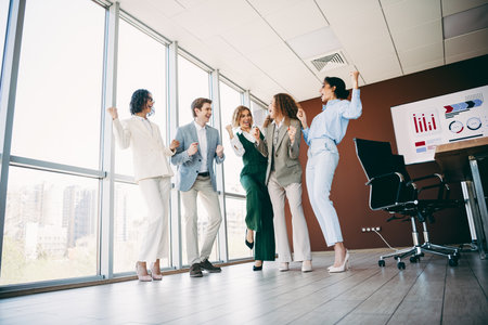 Group of business professionals celebrating teamwork and success in a modern office with city view and collaborationの写真素材