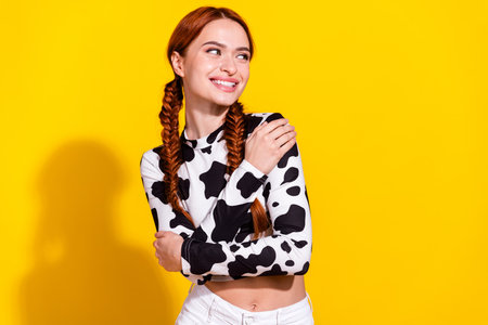 Portrait of cute positive girl hands embrace touch shoulders look empty space isolated on yellow color backgroundの写真素材