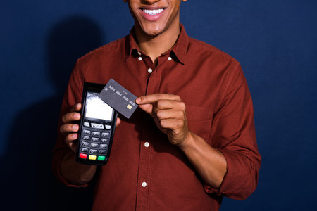 Cropped photo of attractive funny guy wear formal shirt paying credit card terminal isolated blue color backgroundの写真素材