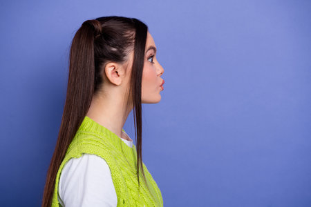 Young woman in neon green sweater in profile pose against purple background for fashion lifestyle stock photoの写真素材