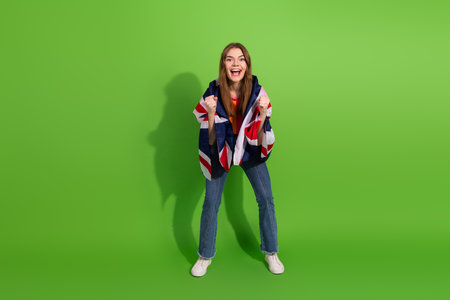 Young woman celebrates with british flag draped over shoulders in front of green screen cheerful excited smiling fashion casual lifestyle advertisingの写真素材