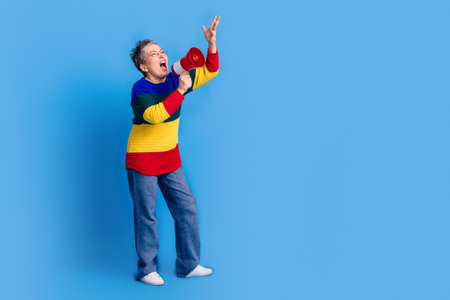Photo of aggressive senior woman wear trendy clothes hold megaphone empty space isolated on blue color backgroundの写真素材