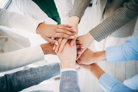 Colleagues collaborating and stacking hands to represent unity teamwork and cooperation in a...
