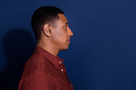 Profile photo of young man look empty space wear brown shirt isolated on dark blue color backgroundの写真素材