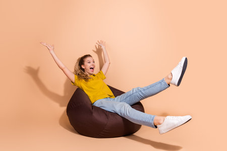 Excited young woman enjoying leisure on a beanbag chair in a vibrant settingの写真素材