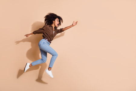 Full length photo of impressed girl wear brown blouse running stretching hand to object in empty...