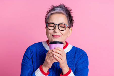 Photo of adorable dreamy lovely woman wear blue stylish clothes hold delicious aromatic coffee isolated on pink color backgroundの写真素材