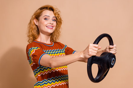Portrait of gorgeous satisfied girl wear ornament t-shirt holding steering wheel buy new vehicle isolated on beige color backgroundの写真素材