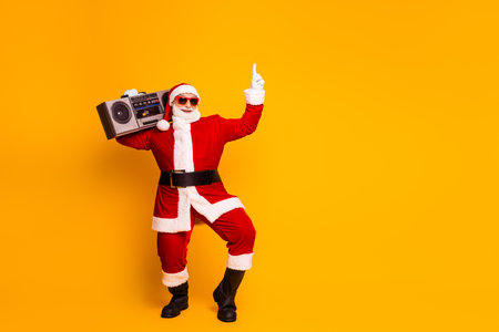 Santa with a boombox on a yellow background wearing red suit hat and beard in a cool funky festive vibeの写真素材