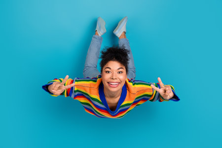 Bright rainbow striped sweater fashion portrait of a young smiling woman against a blue background...