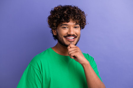 Portrait of a cheerful young man posing joyfully with a friendly gesture in casual green attire on...