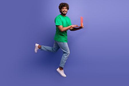 Young man with a laptop presenting modern lifestyle concepts against purple background in casual...