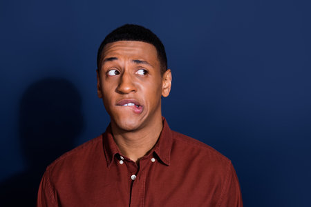 Photo of young man look empty space wear brown shirt isolated on dark blue color background