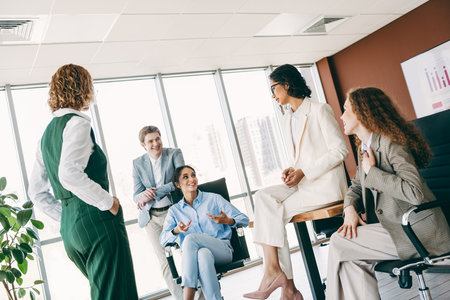 Group of professionals discussing projects in a stylish modern office space with diverse business attire and collaborationの写真素材