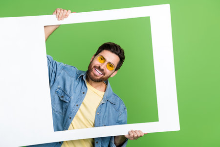 Photo of cool handsome guy wear denim jacket tacking photo isolated green color backgroundの写真素材