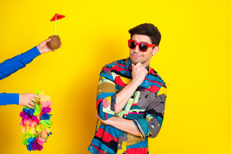 Young stylish male model in colorful shirt and red sunglass posing against a bright yellow...