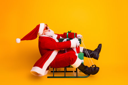 Santa on a festive sled with stacked gifts in a bright scene smiling wearing red suit hat beard and sunglasses perfect for christmas season promotion and holiday saleの写真素材