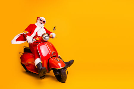 Santa on a bright red scooter brings festive cheer on a sunny yellow background a fun holiday scene perfect for christmas campaignsの写真素材
