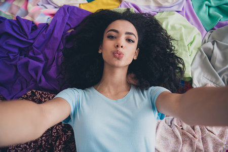 High angle view photo of young girl make selfie kiss lips pile stack clutter clothes apartment...