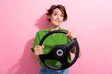 Photo portrait of attractive young woman nervous driver hold steering wheel wear trendy green clothes isolated on pink color backgroundの写真素材