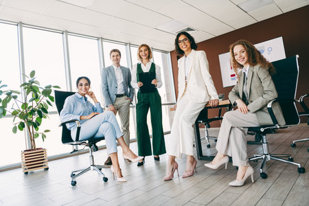 Professional team of diverse colleagues in elegant business attire posing confidently in a modern office environmentの写真素材