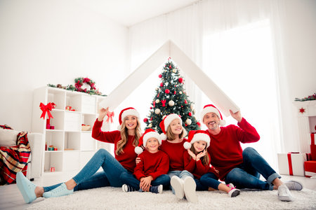 Warm family Christmas scene indoors with tree Santa hats gifts showing love together and festive holiday bondingの写真素材