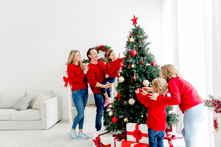 Family gathers for Christmas at home decorating tree and sharing joy with childrenの写真素材