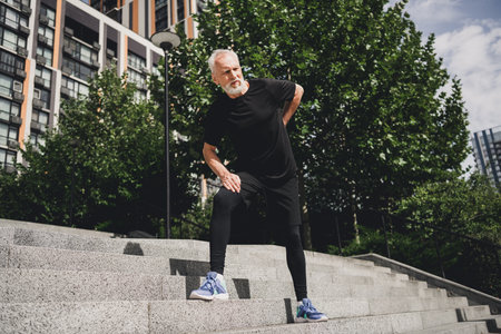 Outdoor city park workout for senior man stretching on steps in urban setting for active lifestyle fitnessの写真素材