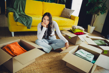 Move in day a young woman sits among open boxes in a bright living room with a yellow couch and...