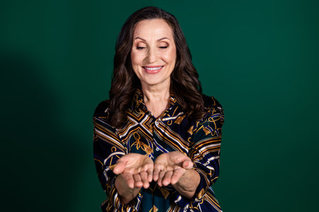 Photo of charming nice senior lady wear stylish clothes hold empty space offer isolated on dark green color backgroundの写真素材