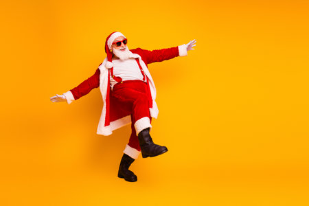 Santa in a red costume dances joyfully yellow backdrop spreading festive holiday spirit Christmas celebrationsの写真素材