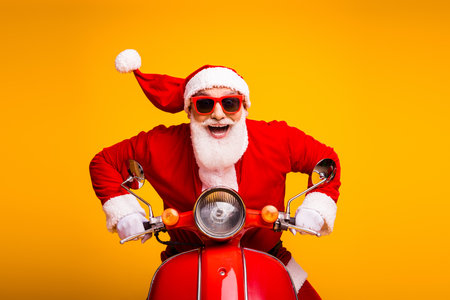 Santa on a bright red motorcycle brings festive fun and Christmas spirit for holiday campaigns and seasonal marketingの写真素材