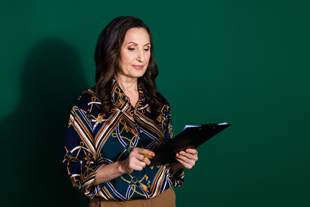 Photo of successful elegant senior lady wear trendy print clothes read cv isolated on dark green color backgroundの写真素材