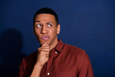 Photo of young man look empty space think wear brown shirt isolated on dark blue color backgroundの写真素材